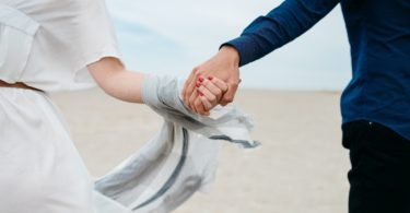 man and woman holding hands together in field during daytime