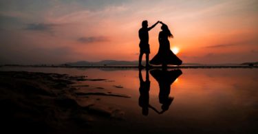 silhouette of man and woman kissing on beach during sunset