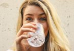 woman in white crew neck shirt drinking water