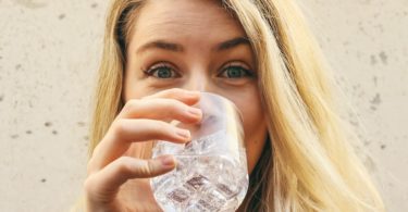 woman in white crew neck shirt drinking water