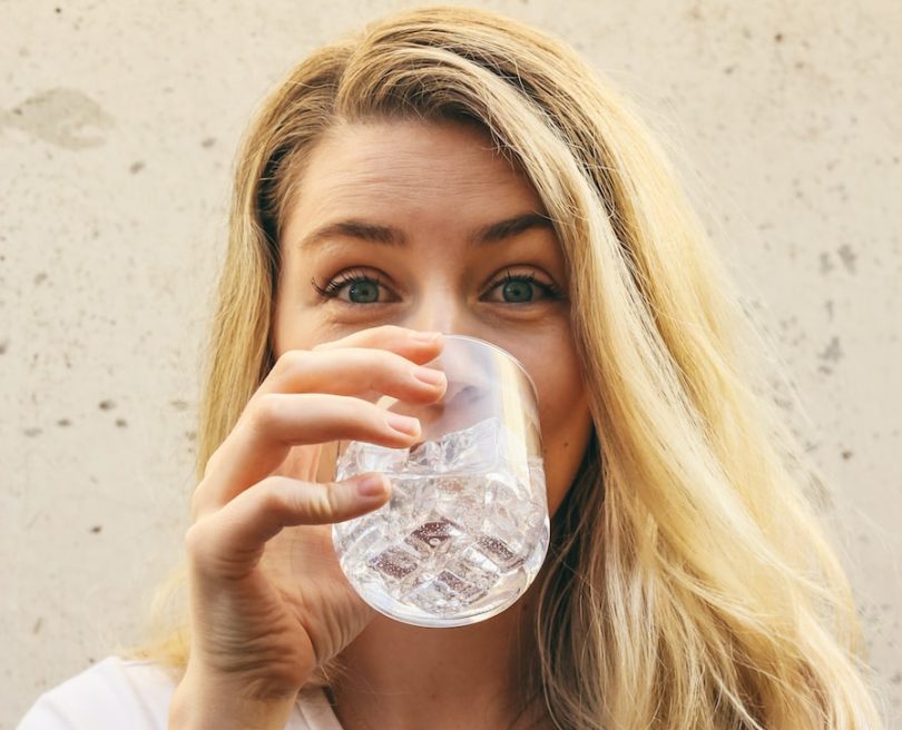 woman in white crew neck shirt drinking water