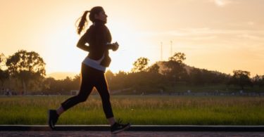 woman in black sports bra and black pants running on water during sunset