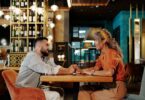 A couple enjoying a romantic date, holding hands in a stylish café setting.