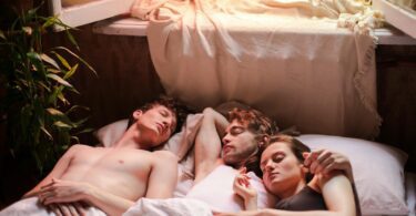 A serene morning scene of three people asleep together in a cozy sunlit bedroom.