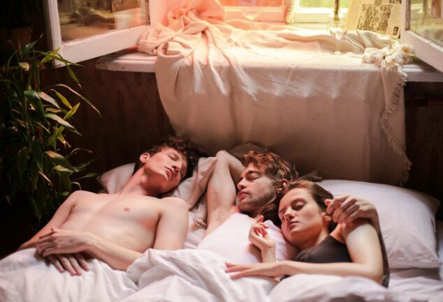 A serene morning scene of three people asleep together in a cozy sunlit bedroom.